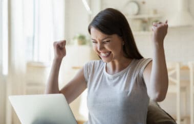 Excited young woman looking on screen of her laptop